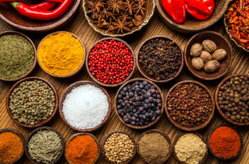 A selection of various colorful spices on a wooden table in bowls